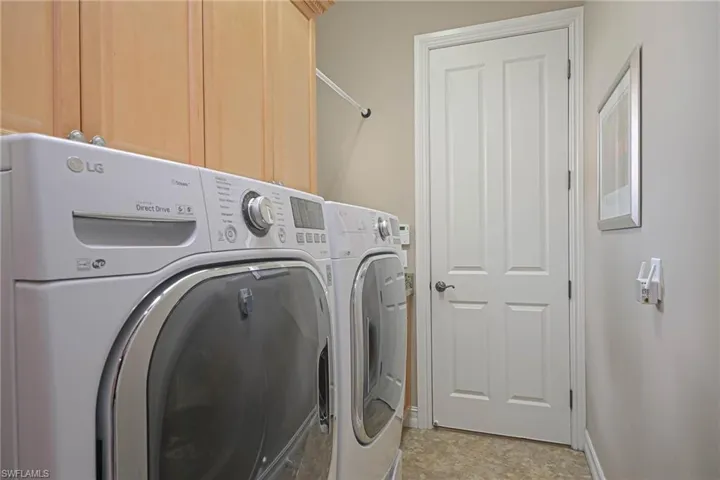 Washroom featuring front load washing machine and dryer and cabinetry