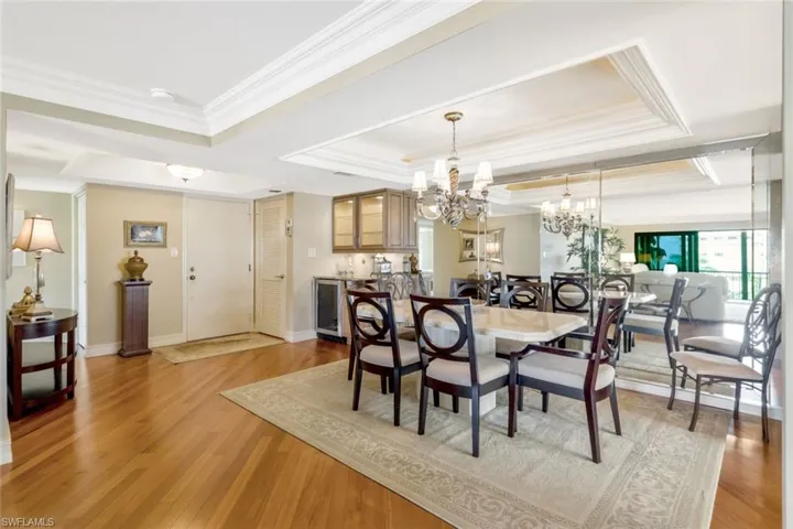 Dining space with a notable chandelier, light wood-type flooring, and a tray ceiling
