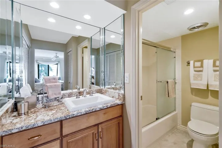 Full bathroom featuring ceiling fan, toilet, enclosed tub / shower combo, and vanity