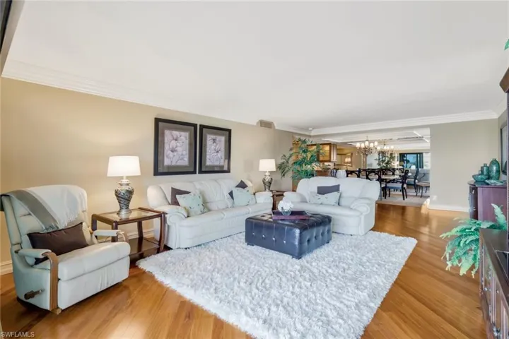 Living room with ornamental molding, an inviting chandelier, and light hardwood / wood-style floors