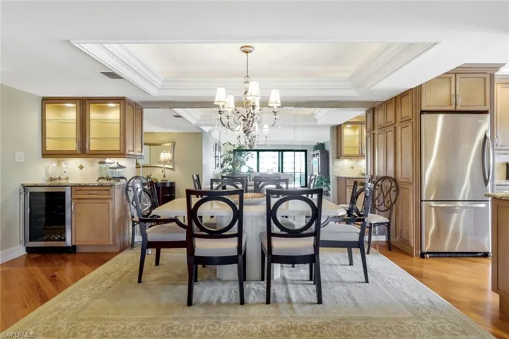 Dining space with beverage cooler, hardwood / wood-style floors, a chandelier, and ornamental molding