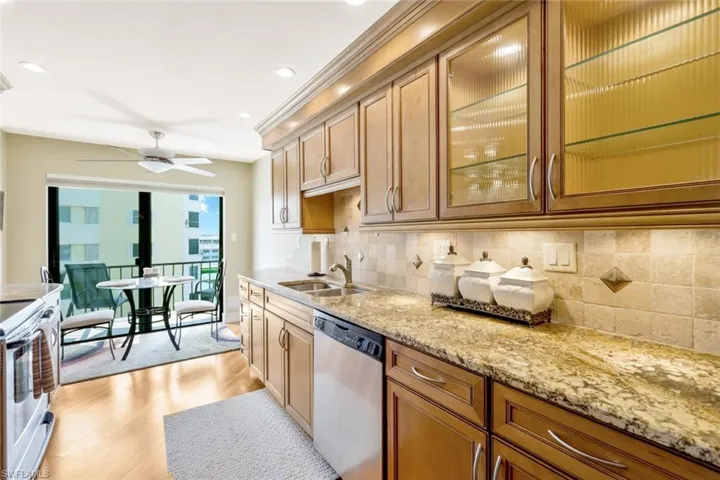 Kitchen with light hardwood / wood-style flooring, sink, ceiling fan, decorative backsplash, and appliances with stainless steel finishes