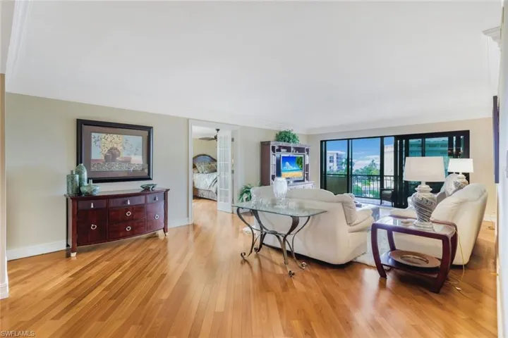 Living room featuring light wood-type flooring, crown molding, and ceiling fan