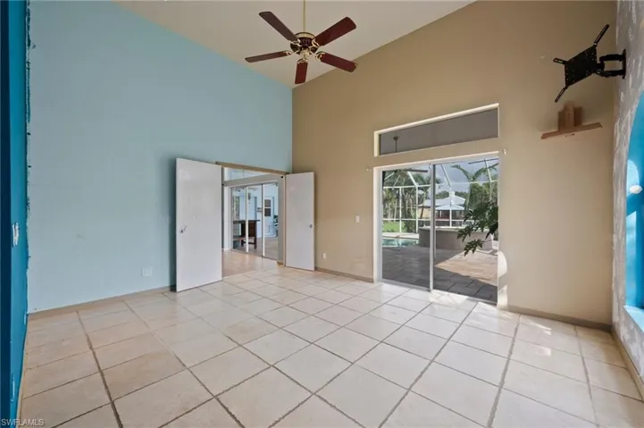 Empty room with light tile patterned floors, a high ceiling, a sunroom, and ceiling fan