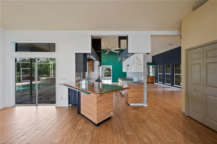 Kitchen featuring light wood-type flooring, modern cabinets, ceiling fan, a peninsula, and dark stone countertops