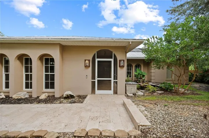 Entrance to property featuring stucco siding, a sunroom, and a metal roof
