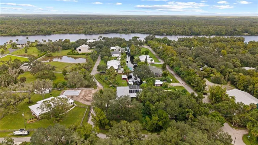 Aerial overview of property's location featuring a nearby body of water and a forest