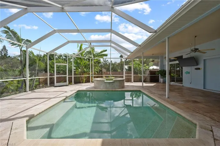 View of swimming pool with ceiling fan, glass enclosure, a patio area, a sunroom, and a pool with connected hot tub