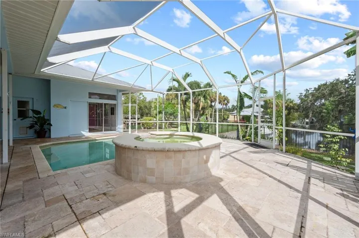 View of swimming pool featuring glass enclosure, a sunroom, a patio area, and a pool with connected hot tub