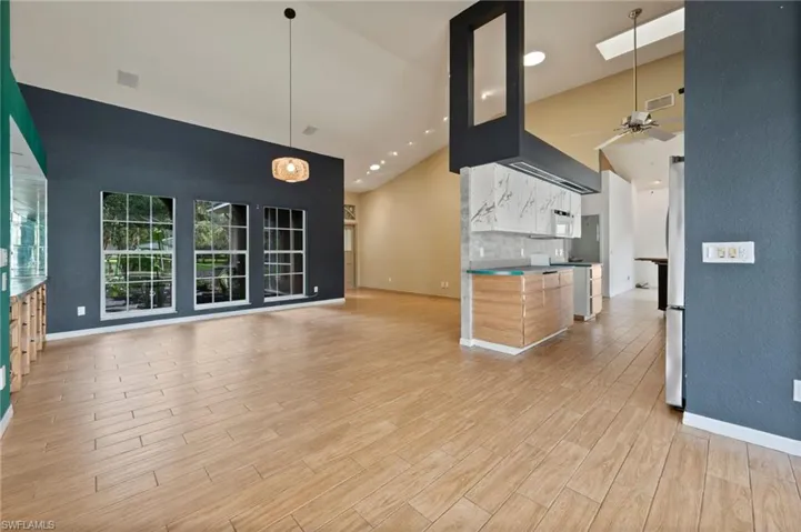 Unfurnished living room with high vaulted ceiling, light wood-style flooring, and ceiling fan
