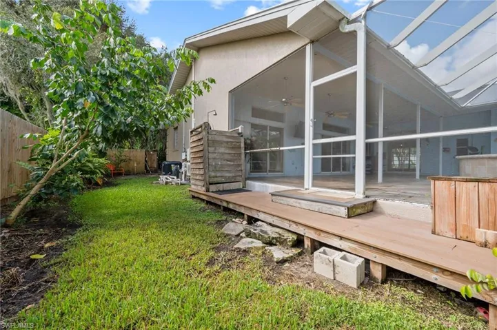 Rear view of house featuring a ceiling fan, a sunroom, a wooden deck, and glass enclosure
