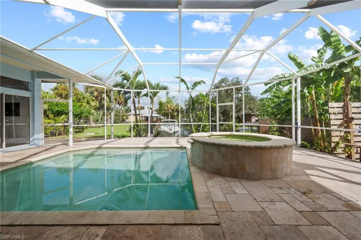 View of swimming pool with a sunroom, glass enclosure, a patio area, and a pool with connected hot tub