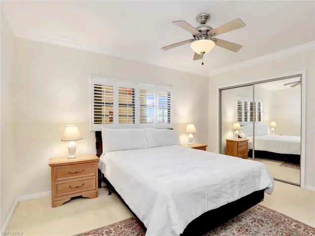 Bedroom with ornamental molding, a closet, light carpet, and ceiling fan