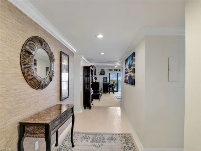 Hallway with light tile patterned floors and crown molding