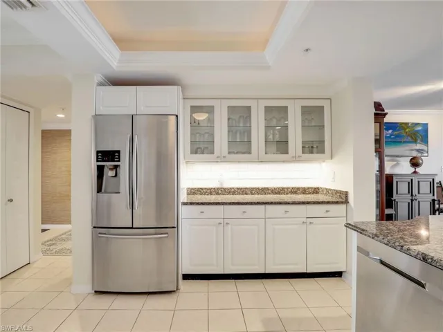 Kitchen featuring appliances with stainless steel finishes, granite countertops, light tile patterned floors, and white cabinets