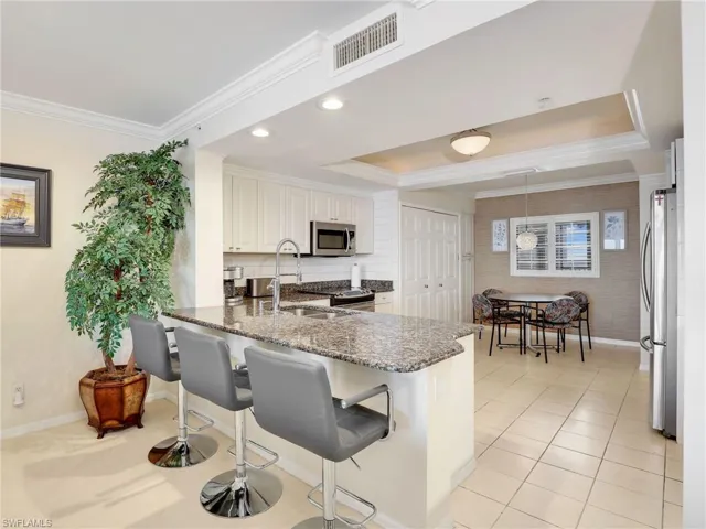 Kitchen with stainless steel appliances, granite countertops, white cabinetry, a kitchen bar, and kitchen peninsula