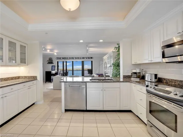 Kitchen featuring white cabinetry, granite countertops, appliances with stainless steel finishes, sink, and kitchen peninsula