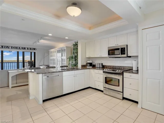 Kitchen featuring granite countertops, white cabinets, kitchen peninsula, sink, and appliances with stainless steel finishes