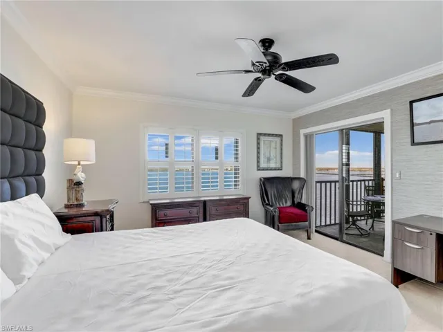 Bedroom with light colored carpet, multiple windows, crown molding, water view, and access to outside