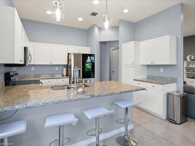 Kitchen featuring a peninsula, white cabinetry, light stone countertops, and recessed lighting