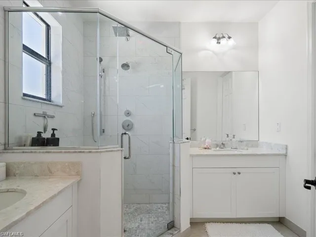 Full bath featuring two vanities and a stall shower