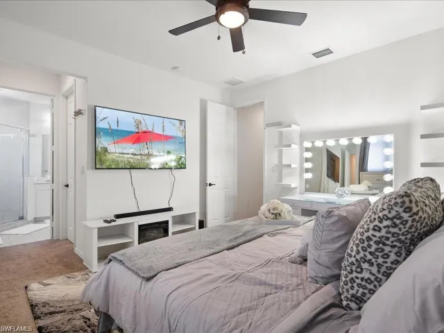 Carpeted bedroom featuring a ceiling fan and connected bathroom