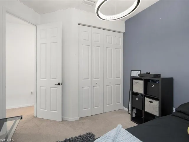 Bedroom with light colored carpet and a closet