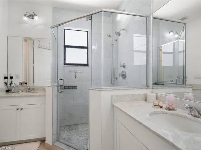 Bathroom featuring two vanities and a shower stall