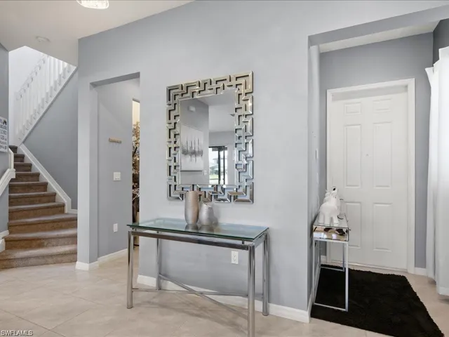 Hallway with light tile patterned floors and stairway