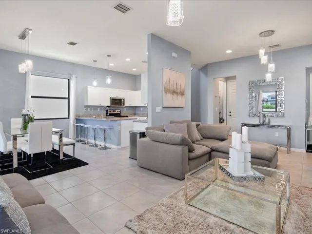 Living area with light tile patterned floors, a chandelier, and recessed lighting
