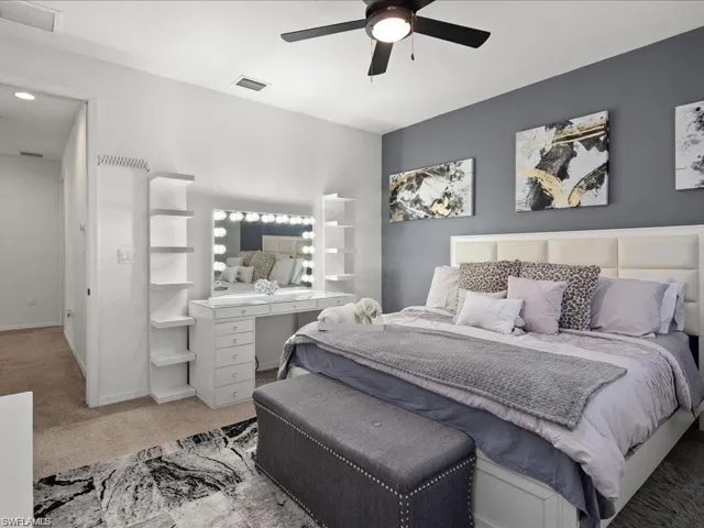 Bedroom featuring light colored carpet, a ceiling fan, and an office area