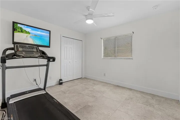 Exercise area with ceiling fan and light tile flooring