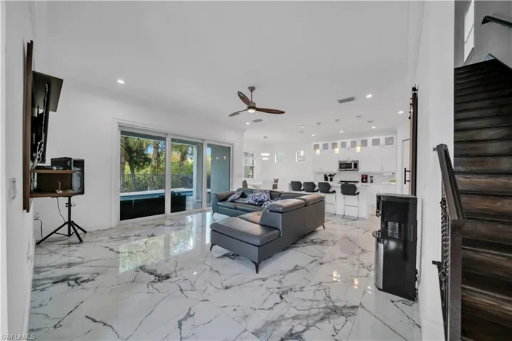 Living area featuring ceiling fan, recessed lighting, and light marble finish flooring