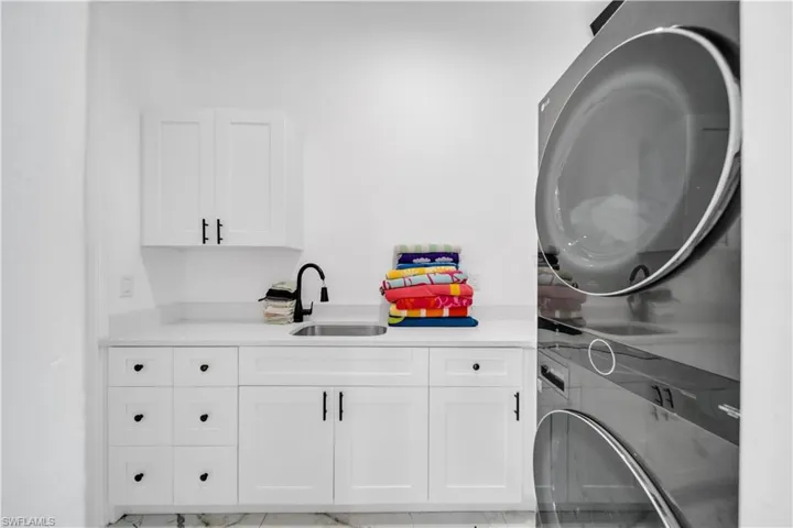 Laundry area featuring cabinet space and stacked washer / drying machine