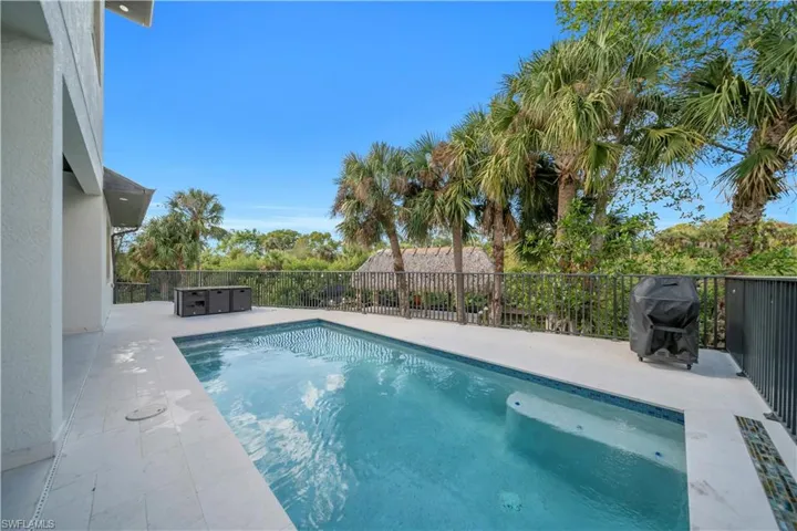 View of swimming pool with a fenced backyard, a grill, and patio surround