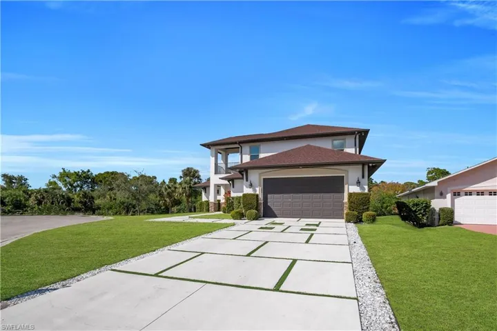 View of front of home with a front yard, driveway, stucco siding, and an attached garage