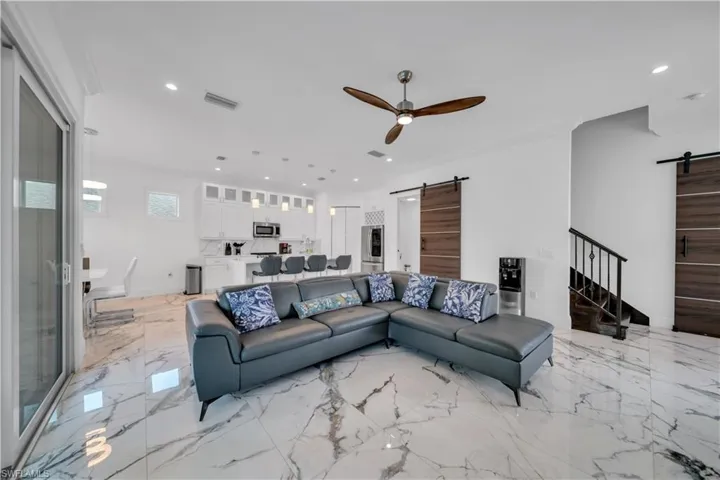 Living room with a barn door, a ceiling fan, and recessed lighting