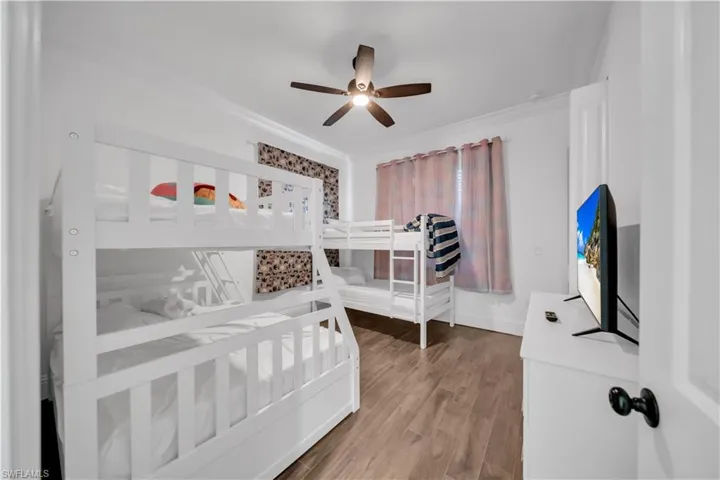 Bedroom with wood finished floors, a ceiling fan, and crown molding