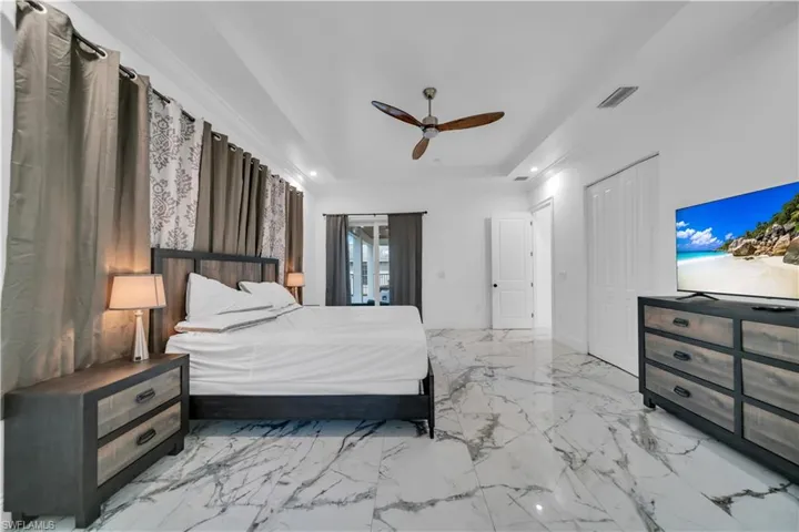 Bedroom with access to outside, a ceiling fan, recessed lighting, a closet, and a tray ceiling