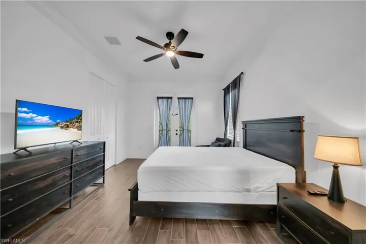 Bedroom with wood tiled floors, access to outside, crown molding, a ceiling fan, and a closet