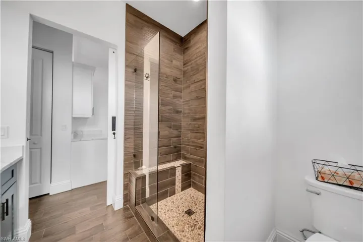 Bathroom featuring a tile shower, vanity, and dark wood-style floors