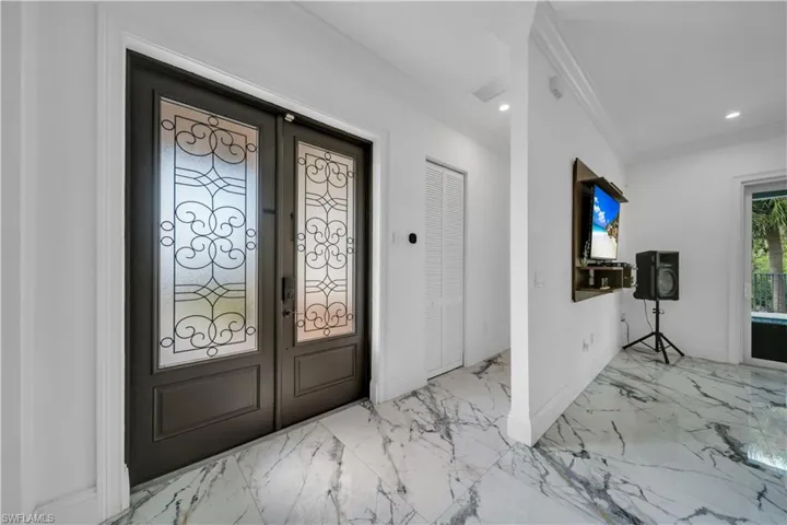 Entrance foyer featuring french doors, ornamental molding, light marble finish flooring, and recessed lighting