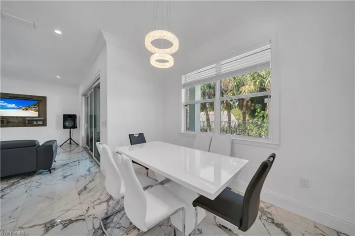 Dining room with crown molding, hanging lights, and light marble finish floors