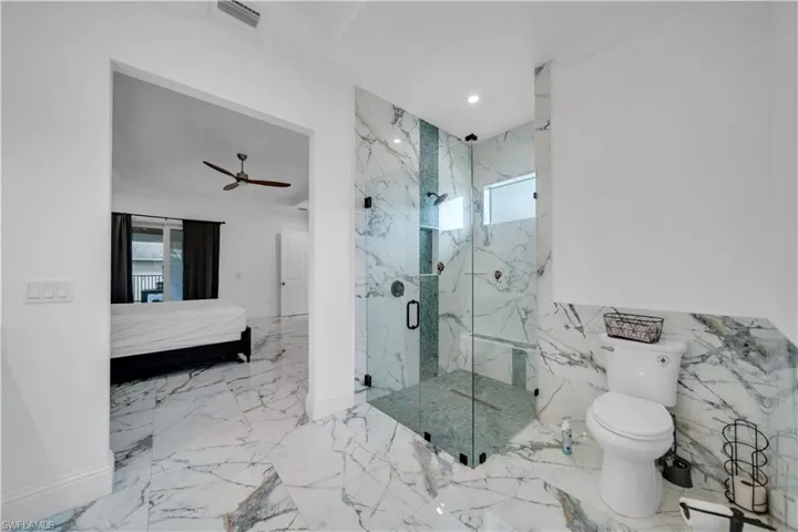 Ensuite bathroom featuring plenty of natural light, a marble finish shower, recessed lighting, and ceiling fan