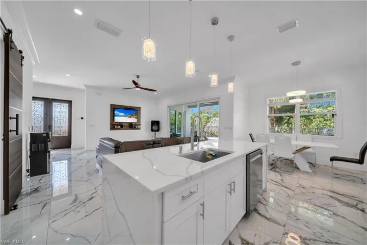 Kitchen featuring a barn door, light stone counters, decorative light fixtures, white cabinetry, and ceiling fan