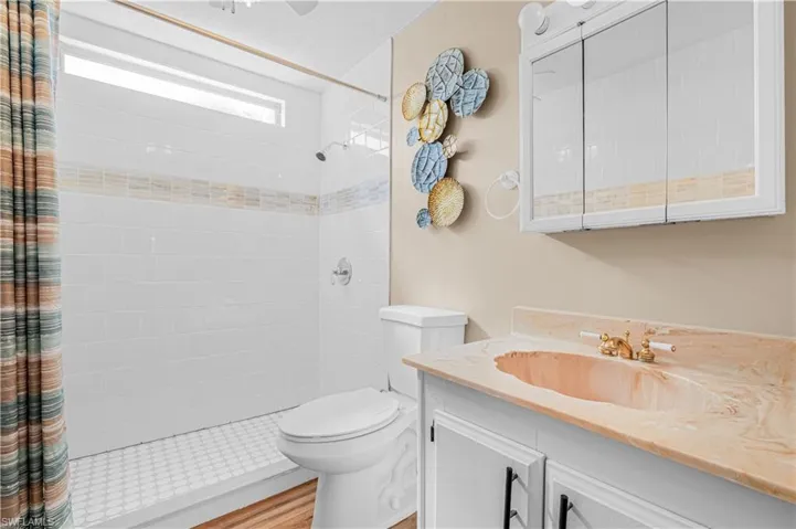 Full bath with vanity, a tile shower, and wood finished floors