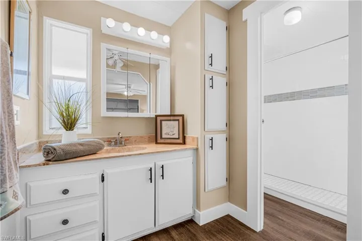 Full bathroom featuring vanity, wood finished floors, and tiled shower