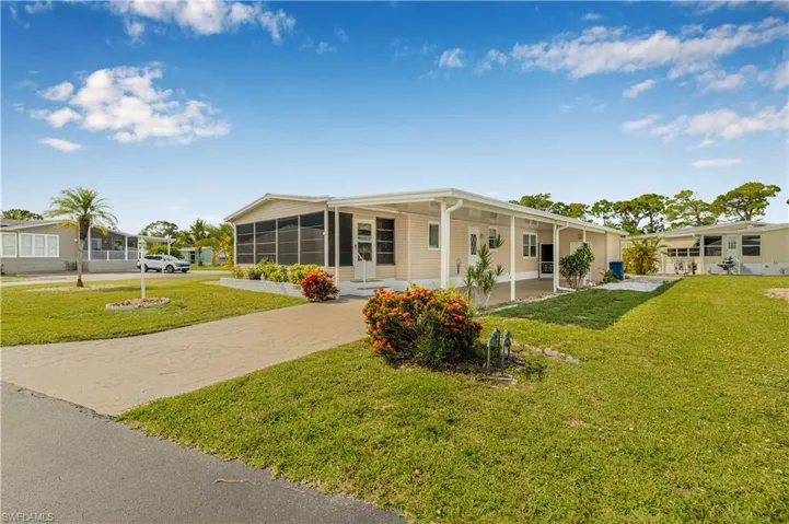 View of front of home featuring concrete driveway, a front yard, a sunroom, and an attached carport