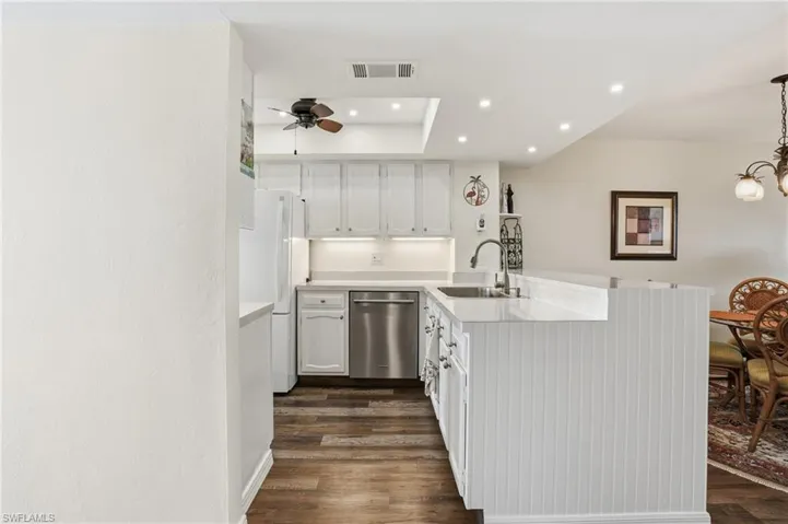 Kitchen with white cabinets, recessed lighting, light countertops, and dishwasher , recessed tray with ceiling fan- Virtually Edited Image