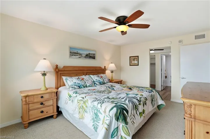 Carpeted bedroom featuring a ceiling fan and a walk in closet - Virtually Edited Image